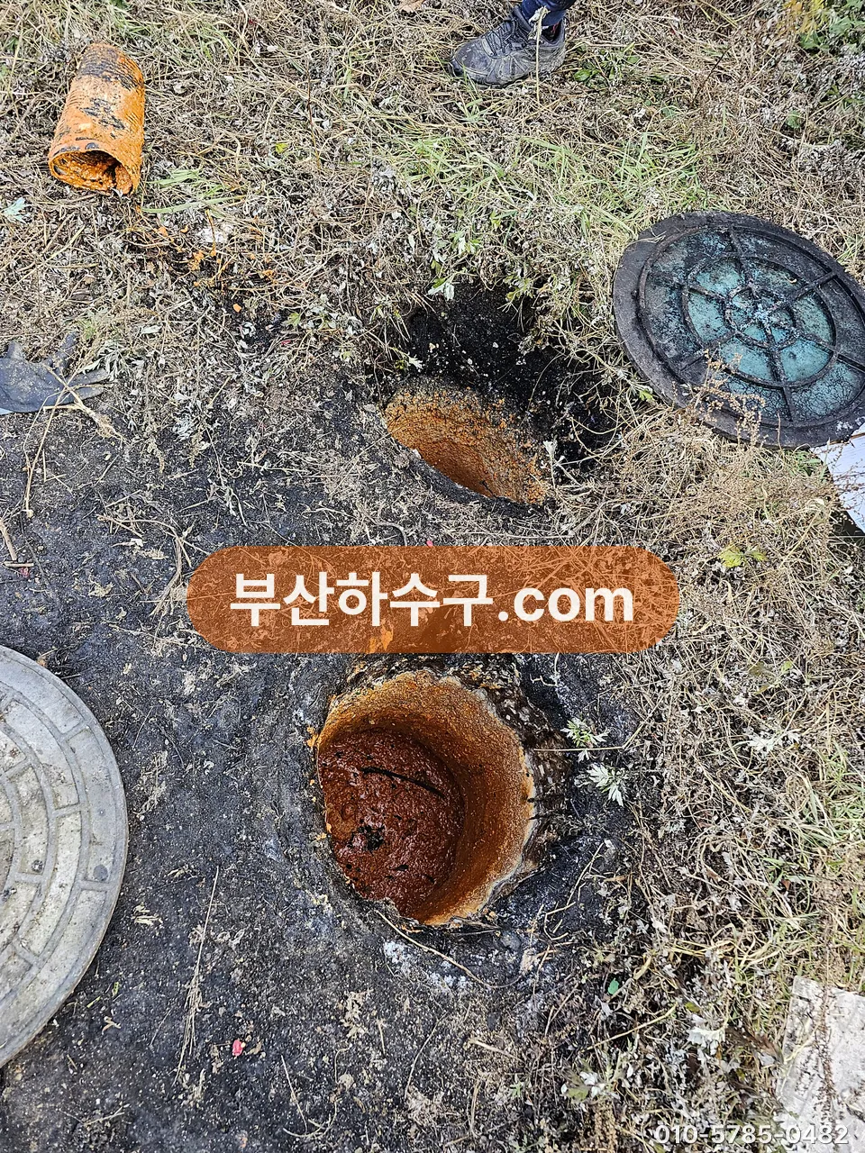 마당 흙바닥에 묻힌 오수받이와 정화조 쪽 맨홀 뚜껑을 열어 연결관 상태를 보는 모습