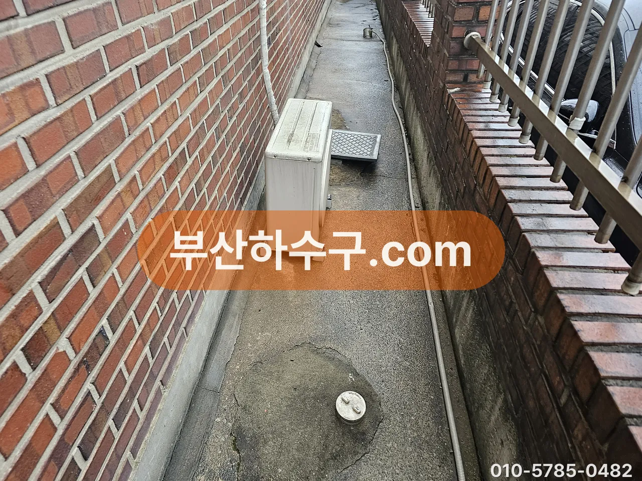 주택 외벽을 따라 내려오는 노출 배관과 골목 바닥, 보온 없이 바람을 그대로 맞는 자리