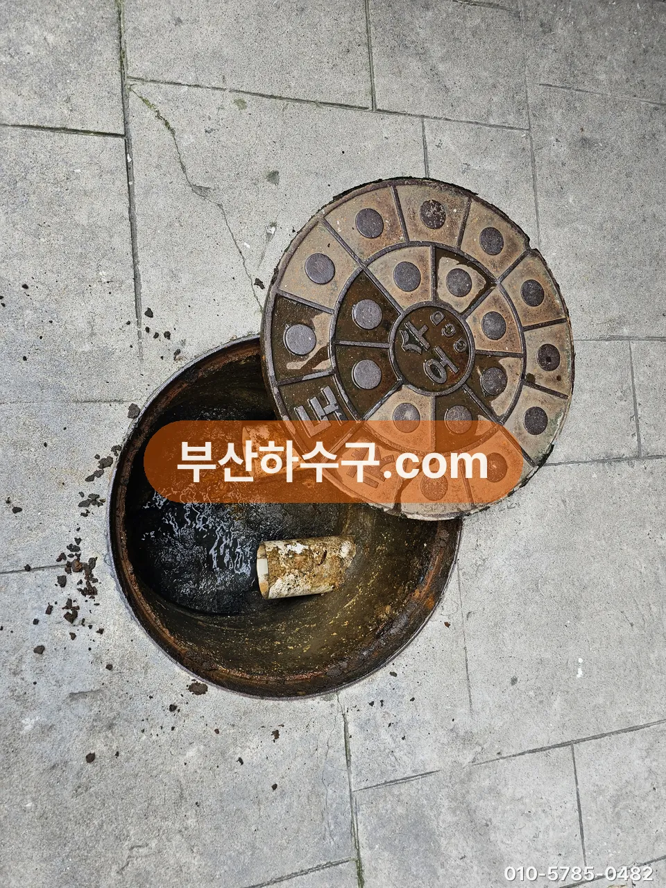 보도 위 오수 맨홀 뚜껑을 열어 세대관과 공용관이 만나는 분기점을 확인하는 장면