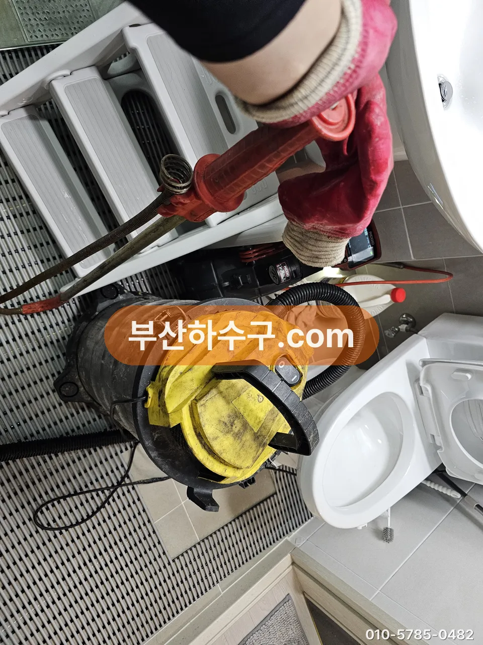 변기 옆에 흡입 장비와 공구를 놓고 작업 준비하는 모습