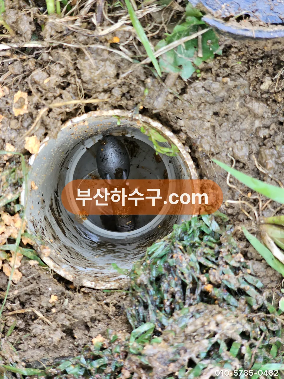 흙에 반쯤 묻힌 옥외 우수관 입구, 토사가 관 안까지 들어찬 모습