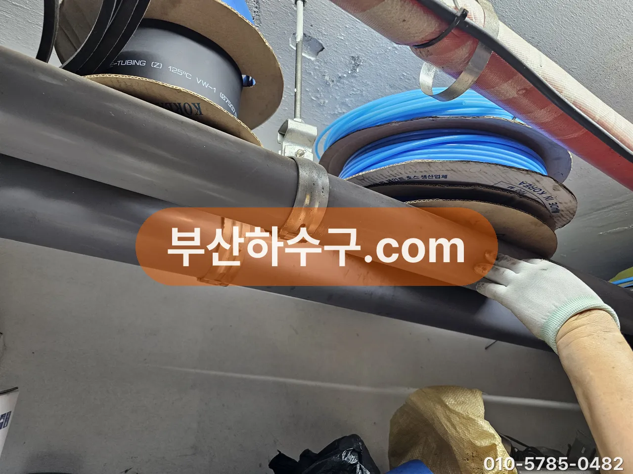 펌프 배출 배관에 연결된 호스와 이음부를 손으로 잡아 상태를 확인하는 모습