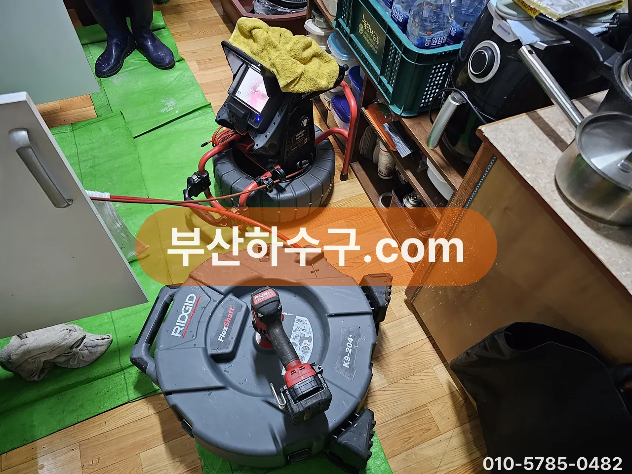 실내 배수구 작업을 위해 바닥에 보호 시트를 깔고 드럼 스프링 장비를 세팅한 모습