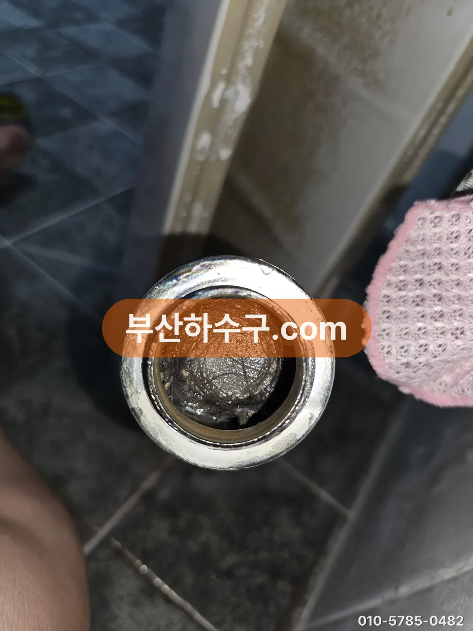 세면대 팝업 몸체를 빼자 배수관 입구를 막고 있던 머리카락 뭉치가 드러난 장면