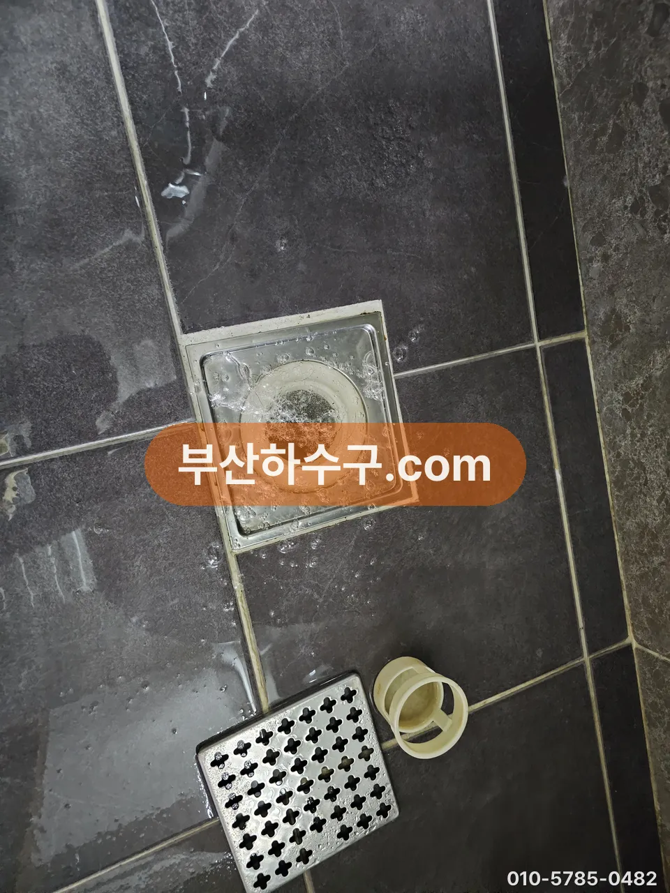 욕실 바닥 유가를 들어내고 옆에 놓은 뒤 배관 입구가 드러난 상태, 트랩 교체 전
